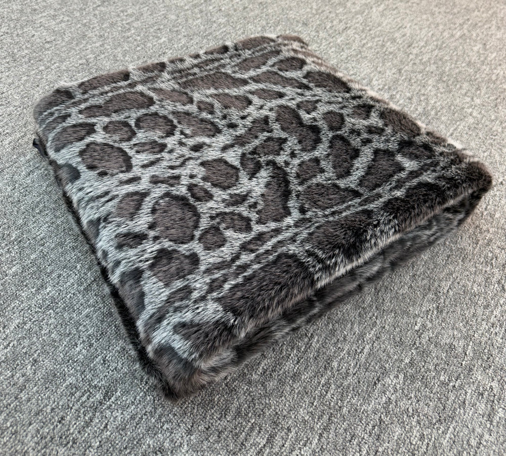 Folded leopard print blanket on a carpeted floor