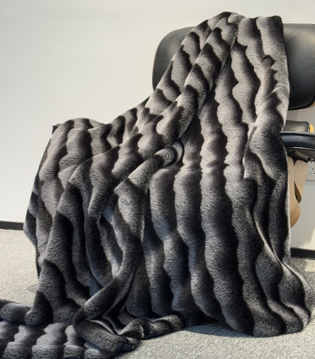 Gray textured throw blanket draped over a chair on a light gray background
