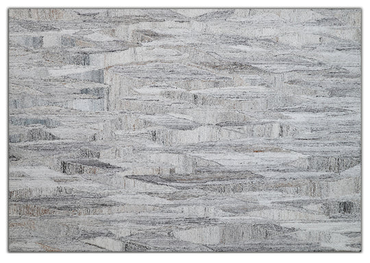 A modern geometric patterned area rug featuring shades of gray and white.