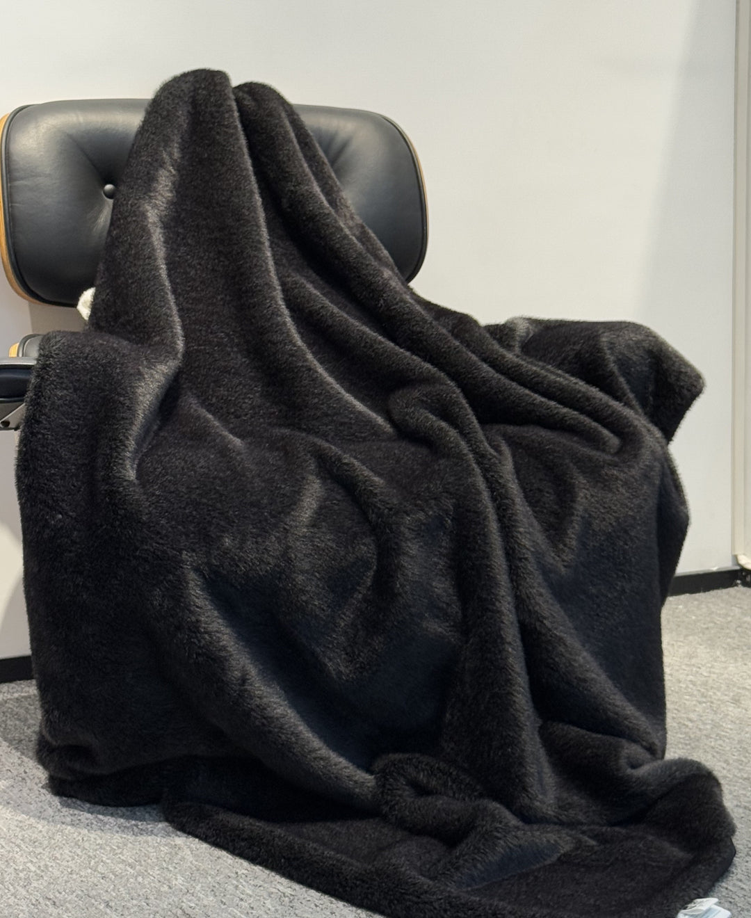 Black blanket draped over a chair against a plain background