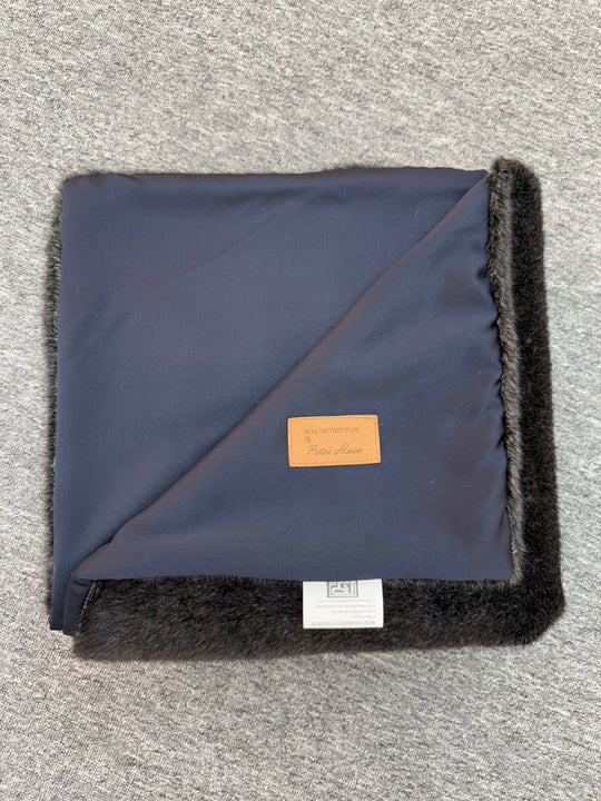 Folded navy blanket with black trim on a gray surface