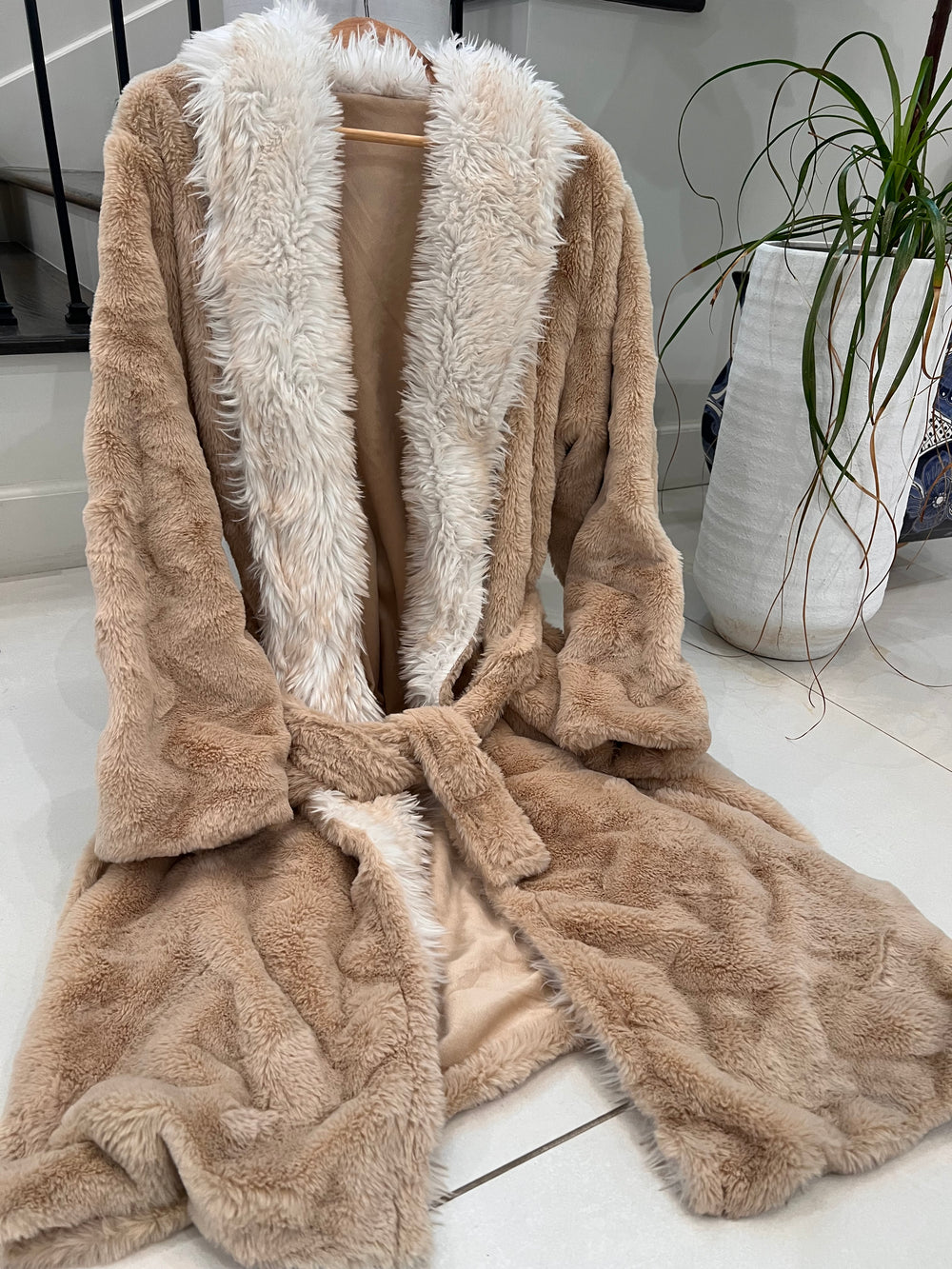 Brown fur coat with white fur trim on a white surface