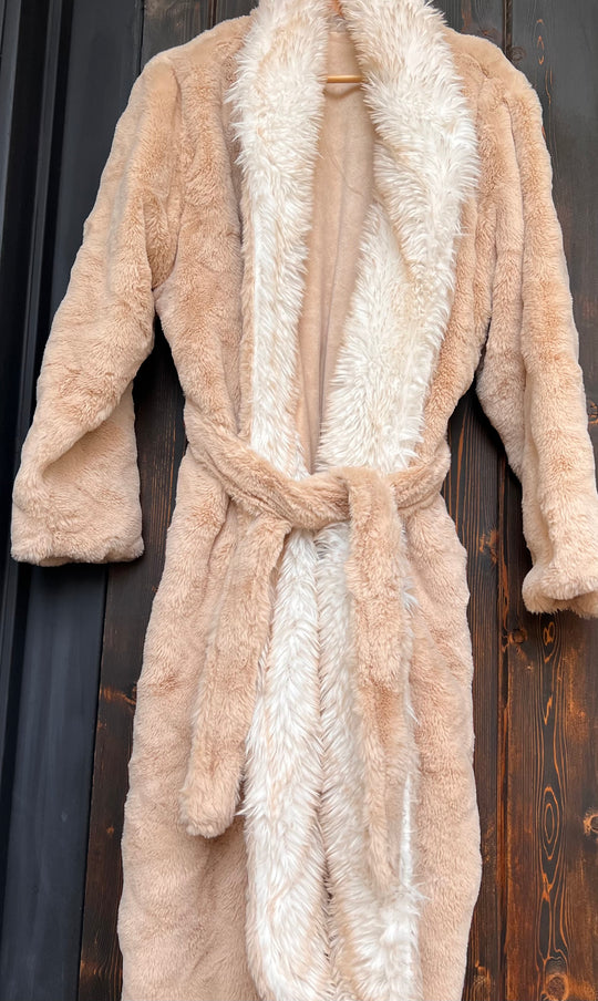 Beige robe with white fur trim on a wooden background