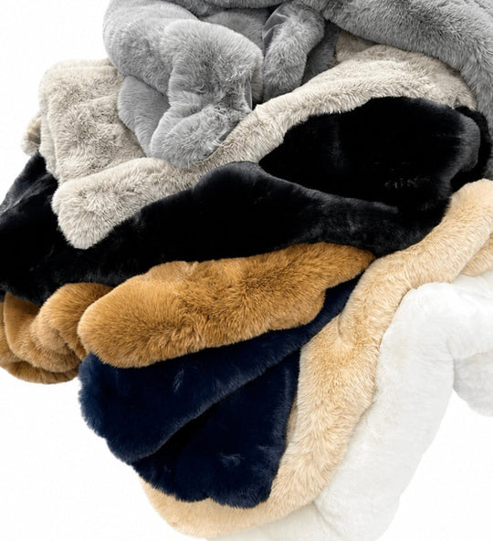 Stack of multicolored plush blankets on a white background