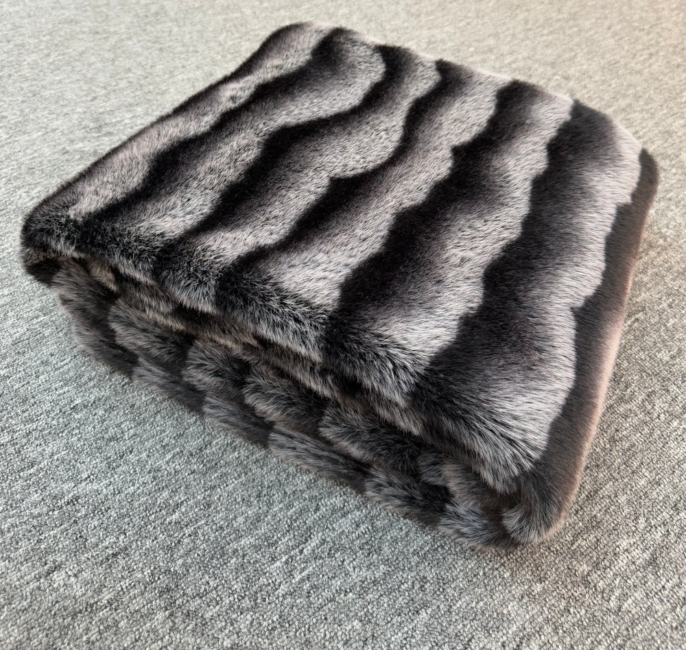Folded fur blanket with a striped pattern on a textured surface