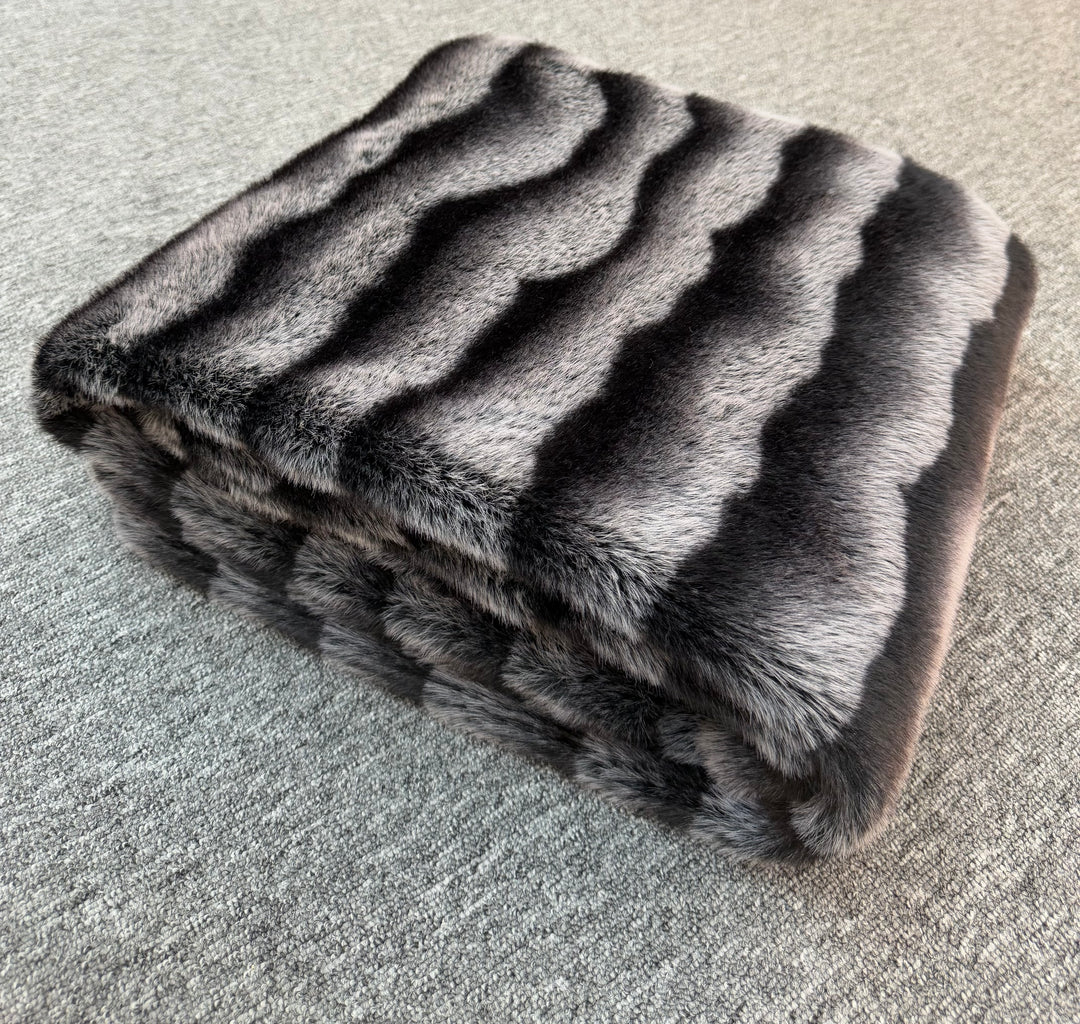 Folded fur blanket with a striped pattern on a textured surface